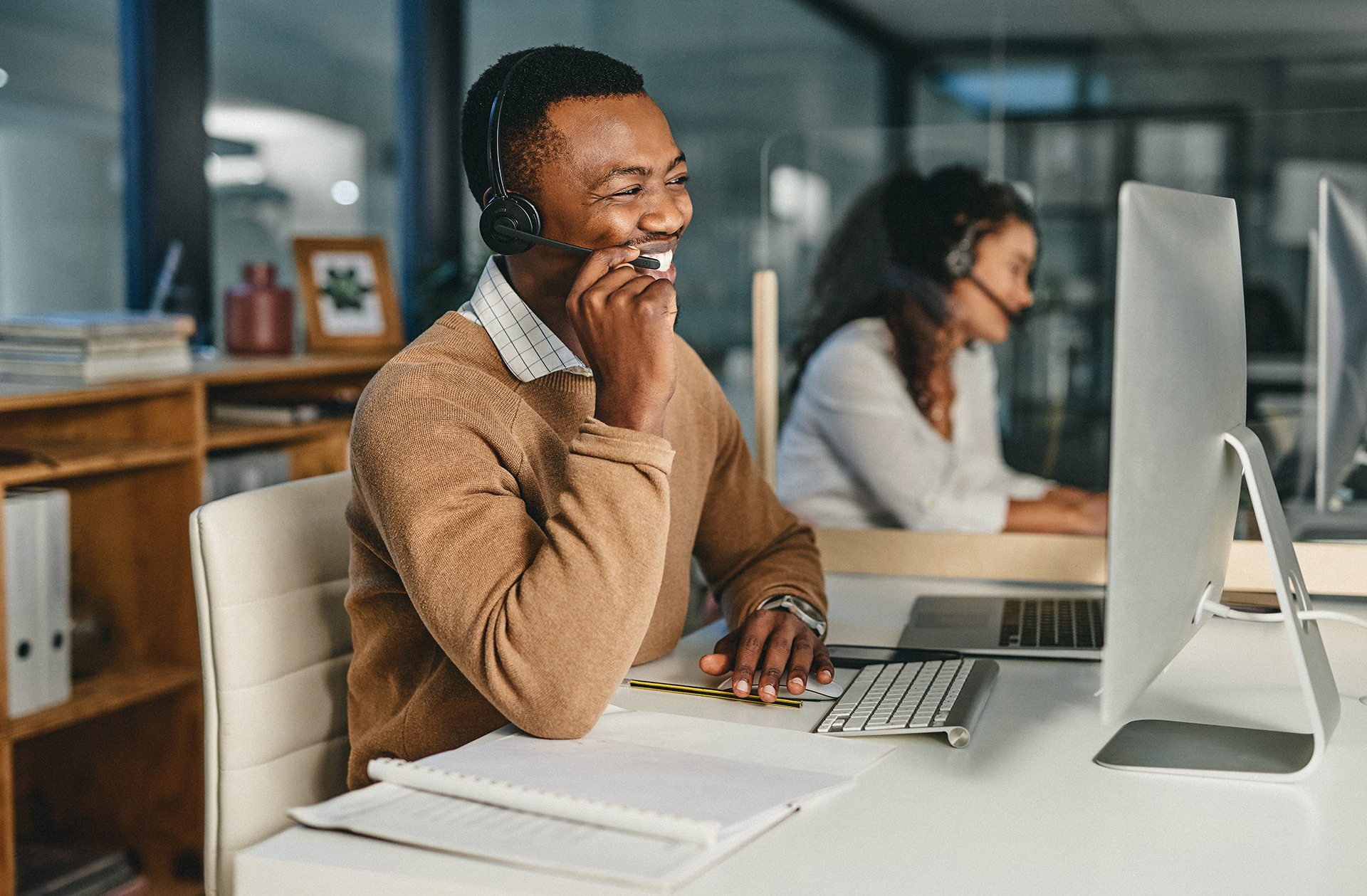 Black male speaking on headset in front of monitor